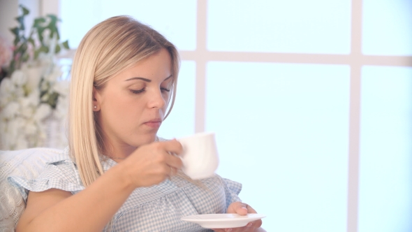 Pregnant Woman Drinking Tea and Talking on Mobile at Home