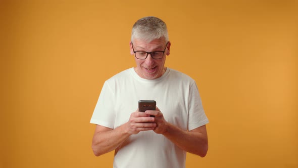 Elderly Retired Man Looking at Telephone Screen Celebrating Getting Message with Good News