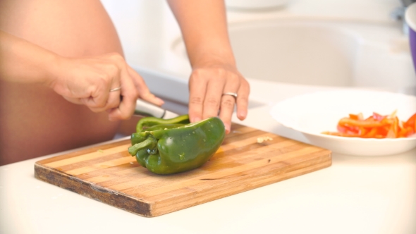 Pregnant Woman Cuts Pepper In The Kitchen. Vegetables For Salad