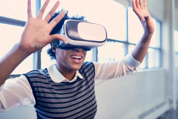 Cool millennial black woman exploring virtual reality glasses in an open-concept space - Stock Photo - Images