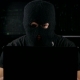 Dangerous Hacker In a Mask Working On a Computer In a Dark Office Room - VideoHive Item for Sale