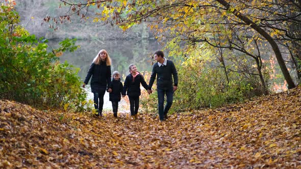 A Happy Family is Walking in the Autumn Park