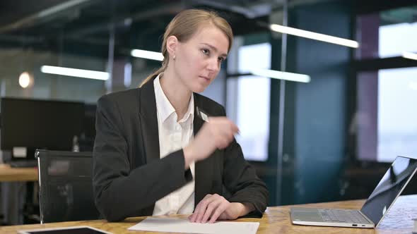 Focused Young Businesswoman Writing on Paper in Modern Office alt