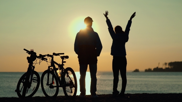 Sunset On The Sea. Sun Reflected In Water. Man And Woman With Bicycles