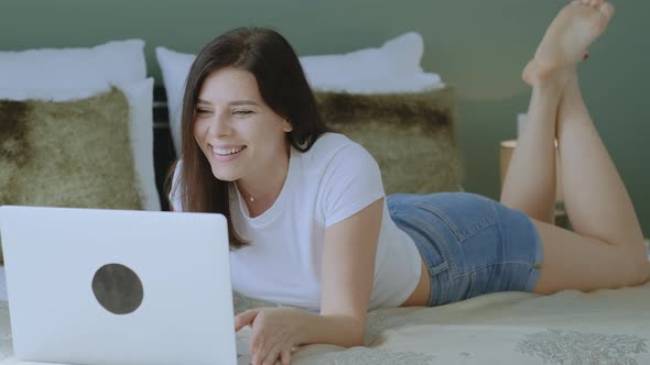 Brunnette woman greeting and talking with friends at video chat using laptop alt