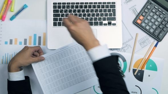Top View Of Businessman Working At Office Desk Twith Laptop, Financial Infromation. Above View. alt