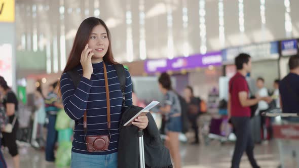 Young female traveler talking with smartphone to someone at airport alt