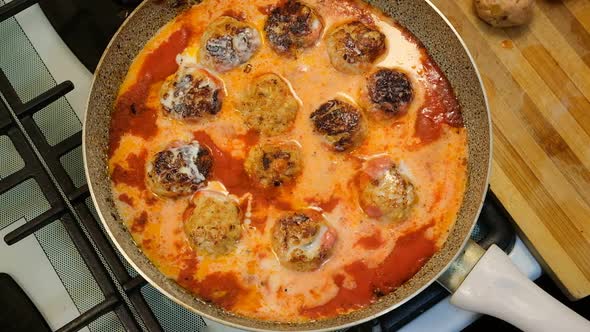 Pour Milk in Tomato Sauce Meatballs in a Pan and Mix with Silicone Spatula