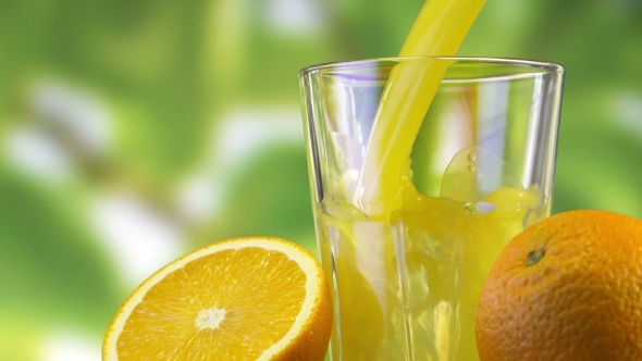Orange Juice Pouring In Glass On Color Background