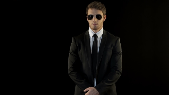 Male Bodyguard Folds His Hands In Front Of His Stomach alt