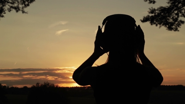 Woman Putting On The Headphones, Listening To Music And Dancing In The Forest