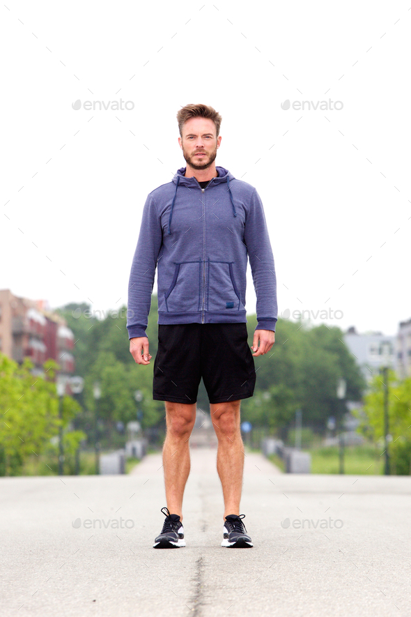 Attractive male athlete standing in middle of street