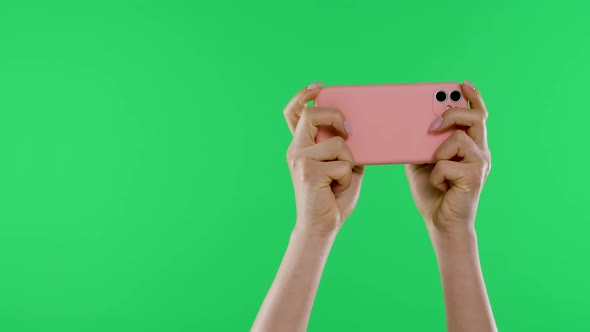 Female Hands Hold the Smartphone Horizontally Against the Background of the Green Screen of the alt