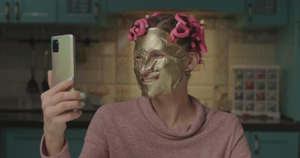 Young 30s Woman Recording Funny Video of Applying Face Cosmetic Mask at Home. Funny Female Blogger alt