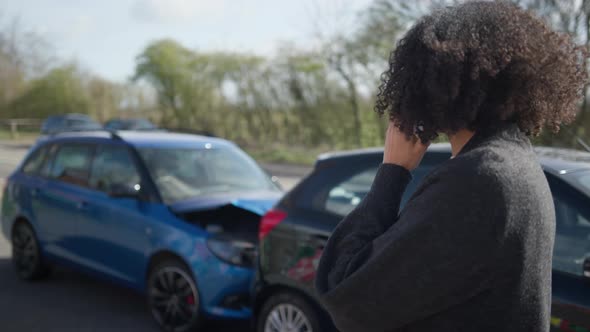 Young woman standing by damaged car after traffic using mobile phone