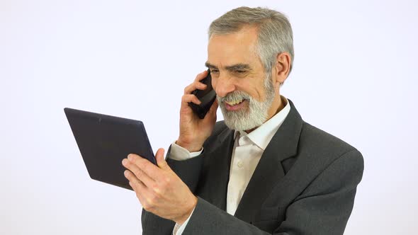 An Elderly Man Holds a Tablet and Talks on a Smartphone - White Screen Studio alt
