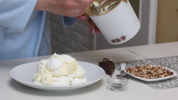 A Woman Prepares A Cake Count Ruins From Meringue. Coats Meringues With Cream, Stacked On A Plate alt