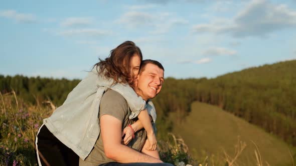 A Young Woman Hugs Her Boyfriend and Laughs. Happy Couple in the Park