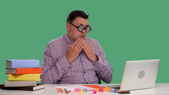 The Man Sits at the Table Uses a Laptop Types on the Keyboard Frightened Covers His Mouth with His alt