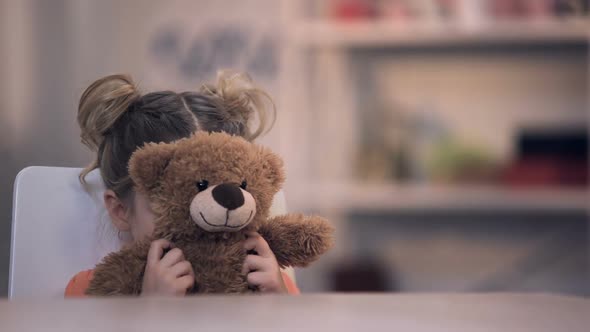 Sad Female Kid Covering Face by Teddy Bear Toy, Family Problem, Loneliness Abuse alt