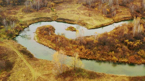 Aerial view of autumn forest and river with colorful trees.
