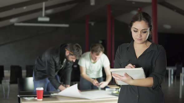 Portrait of a Fashionable Young Professional Woman Holding Folders with Papers and Taking Notes in a alt