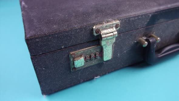 Person Presses Button To Open Old Dirty Case on Light Blue alt