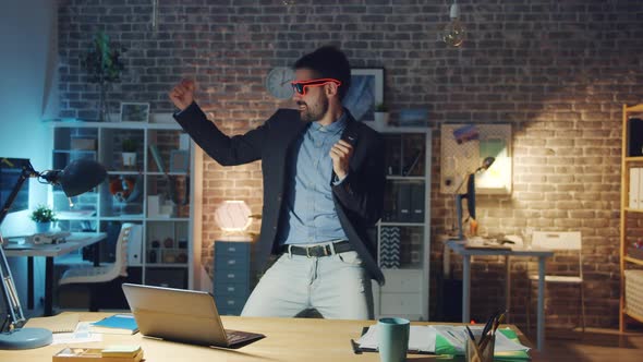 Handsome Office Worker in Stylish Glasses Dancing in Office Room at Night alt