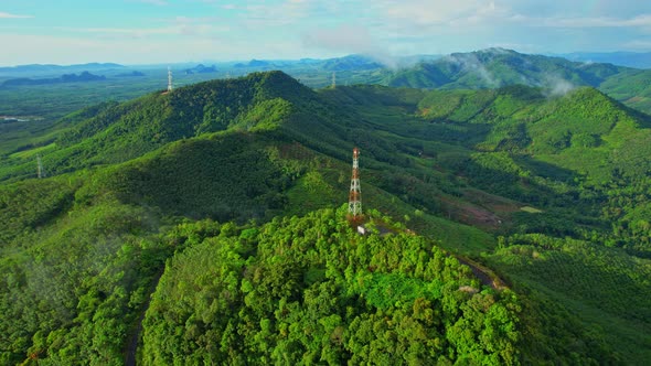 Drone flying over over telecommunication towers on green mountain alt