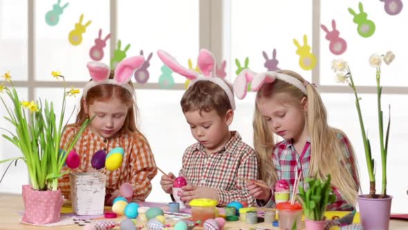 Happy Children Wearing Bunny Ears Painting Eggs on Easter Day