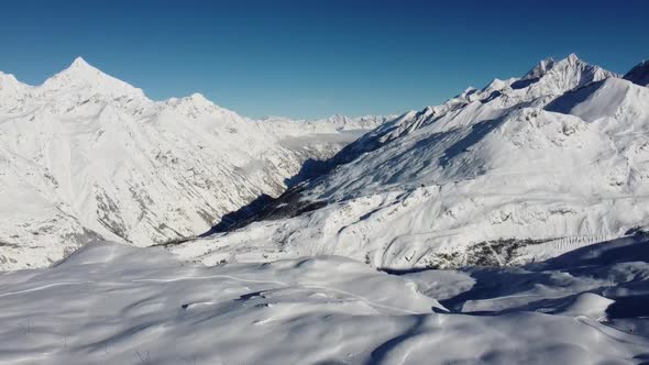 a little fog comes from the valley into the snow-capped mountains in sunny weather in the swiss alps alt