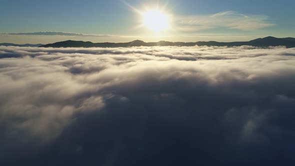 Flying Above the Clouds in the Mountains. Landscape with Sun, Mountains and Dense Shroud of Clouds alt