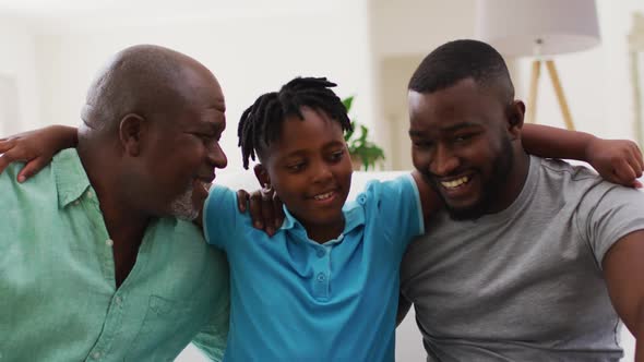Portrait of african american grandfather, father and son smiling together at home alt