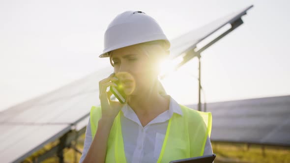 Close Up Portrait of Beautiful Female Technologist Talking on Mobile Phone Among Field of Solar alt