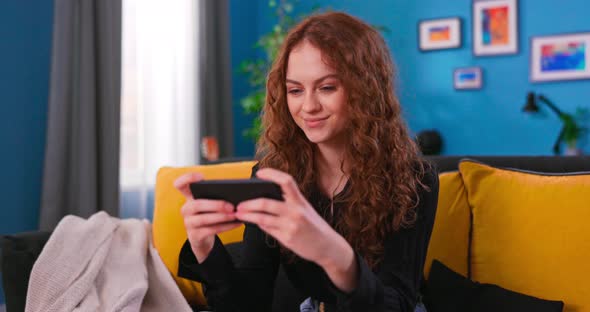 Portrait of a Beautiful Female with Curly Hair in Stylish Cozy Living Room Playing a alt