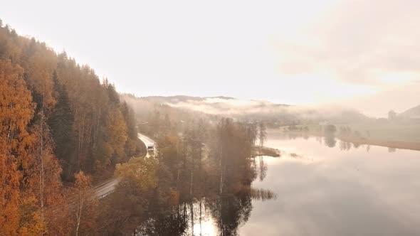 Misty mountains and road near a flat calm lake alt