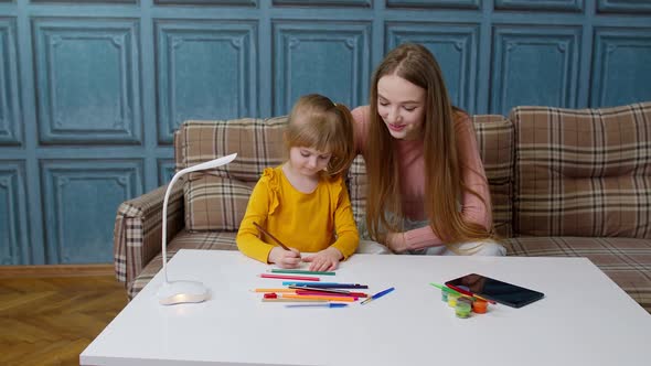Cute Small Child Kid Daughter Learning Drawing Homework with Young Mother Home Distance Education alt