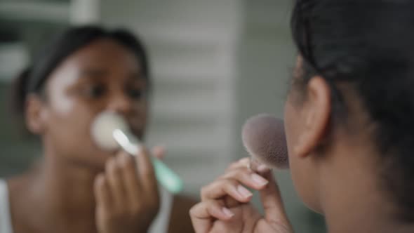 African-American woman applying make up blusher in the bathroom. Shot with RED helium camera in 4K. alt