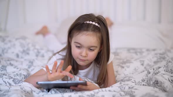 Cheerful Girl Using Tablet on Bed alt