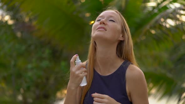 Shot of a Young Woman Applying an Antimosquito Repellent Spray on Her Skin alt