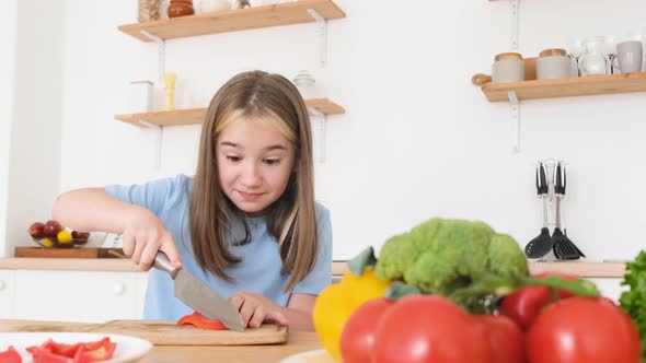 A Teenage Girl Cooks in the Kitchen She Cuts Red Pepper alt