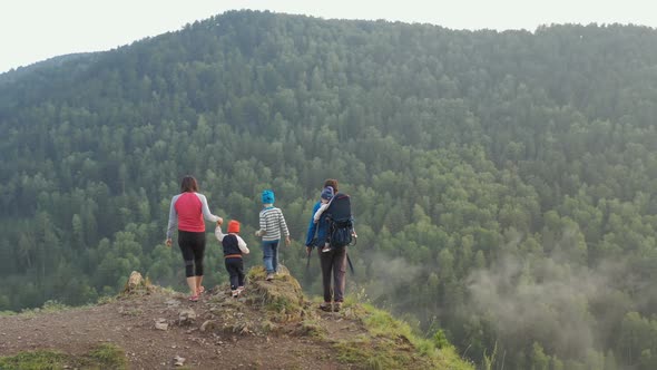 Young Parents with Three Children Climb To the Top of the Mountain and Enjoy the Beautiful View alt