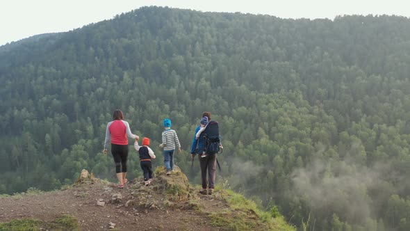 Young Parents with Three Children Climb To the Top of the Mountain and Enjoy the Beautiful View
