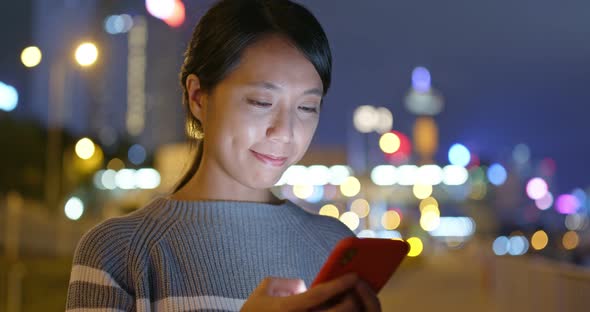 Woman work on smart phone in city at night