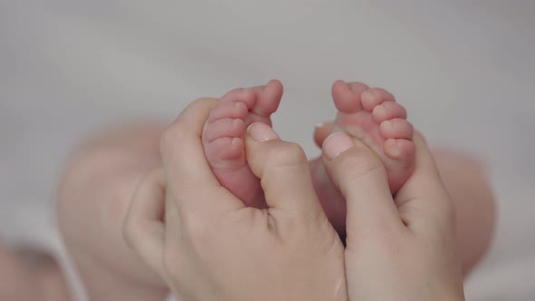 Close Up of Female Hands Massaging Foot of Her Newborn Baby alt