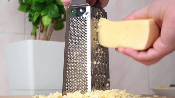 A Man Rubs Cheese on Metal Grater for Freezing and Further Cooking Pizza Pasta