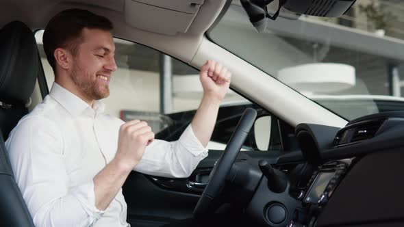 Happy Man Sits in New Car in Shop Dealership and Celebrate Purchase of New Vehicle alt