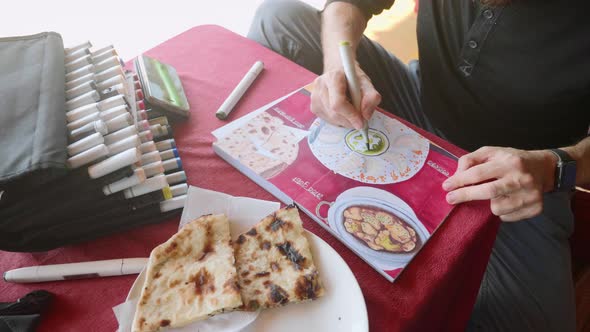 Man Sits in Cafe and Drawing Image of Indian Food in Sketchbook By Art Markers