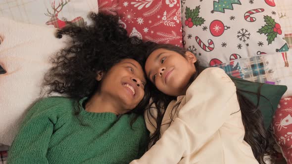 Mother and Schoolgirl Hug on Bed in Christmas Atmosphere alt