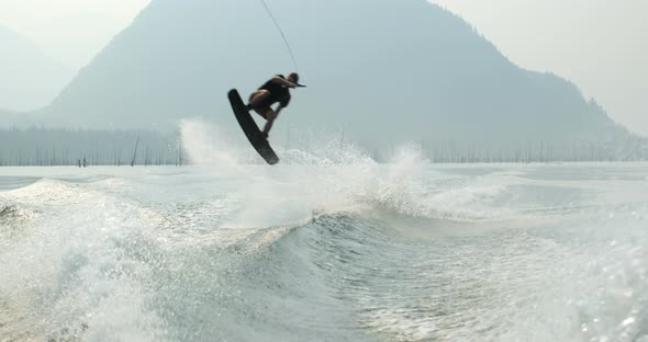 Front view of caucasian young man doing tricks on wakeboard in the city river 4k alt